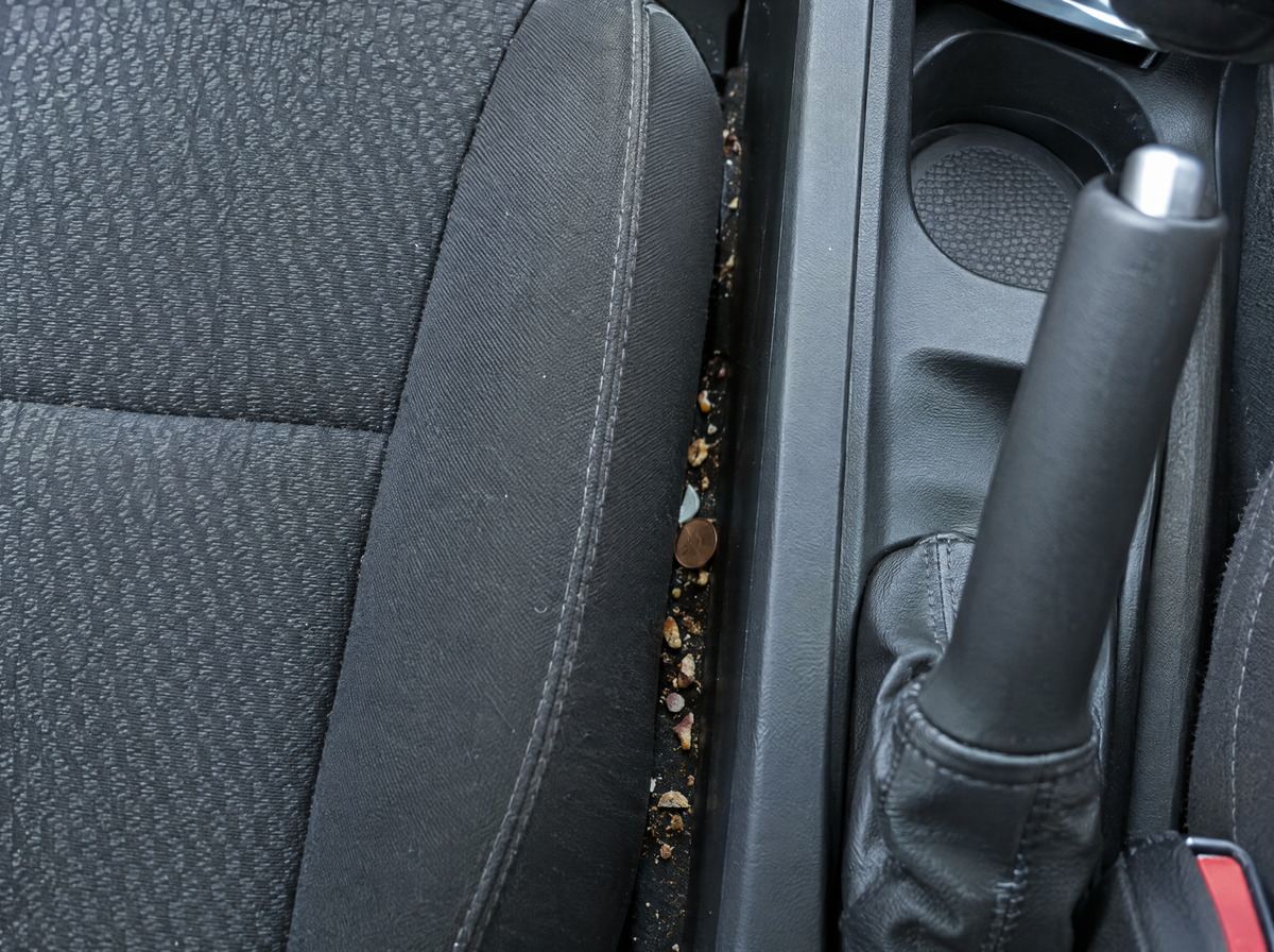Crumbs and a coin wedged in the gap between a car seat and the centre console